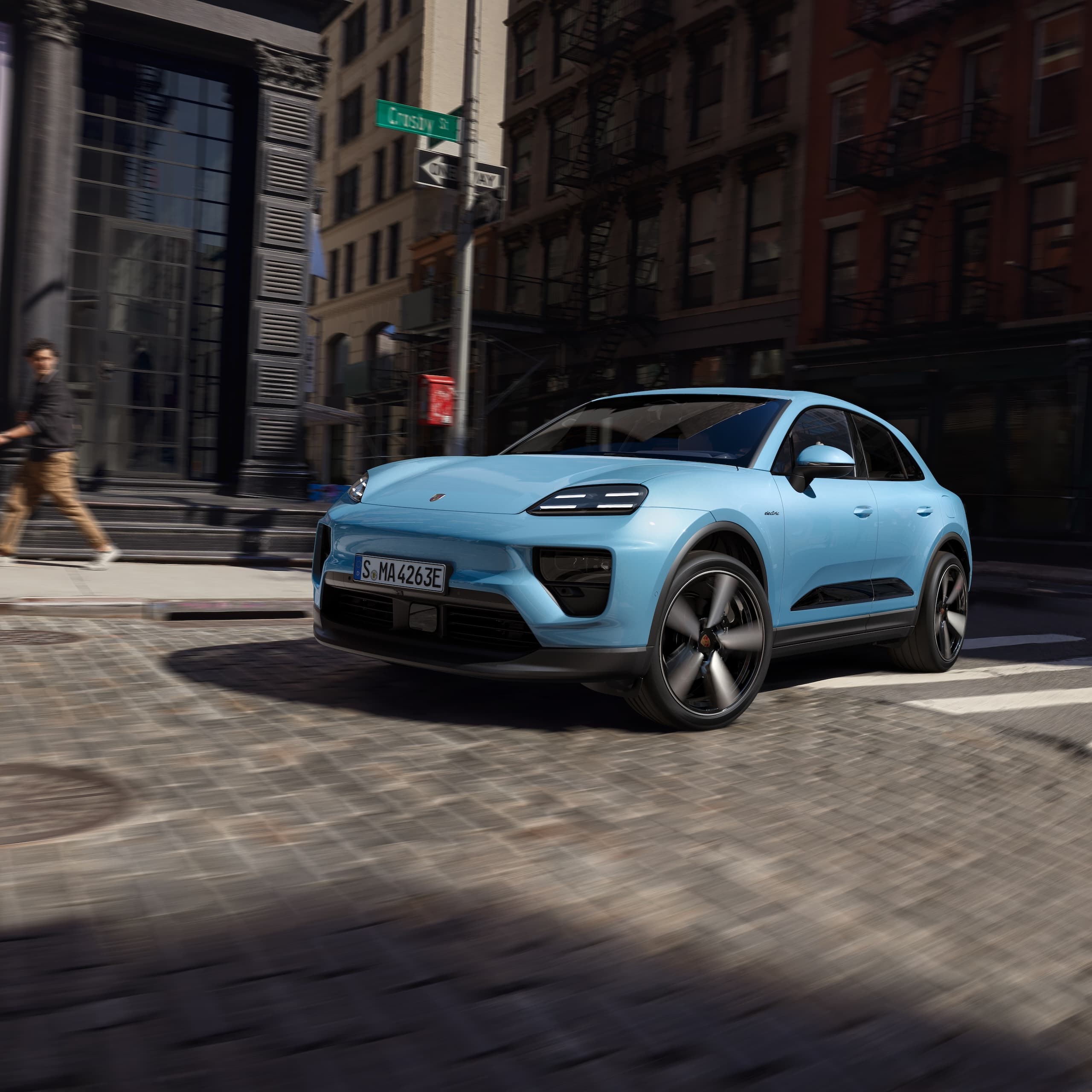 Ein Porsche vollelektrischer Macan, der in einem urbanen Szenario eine Straße hinunterfährt.